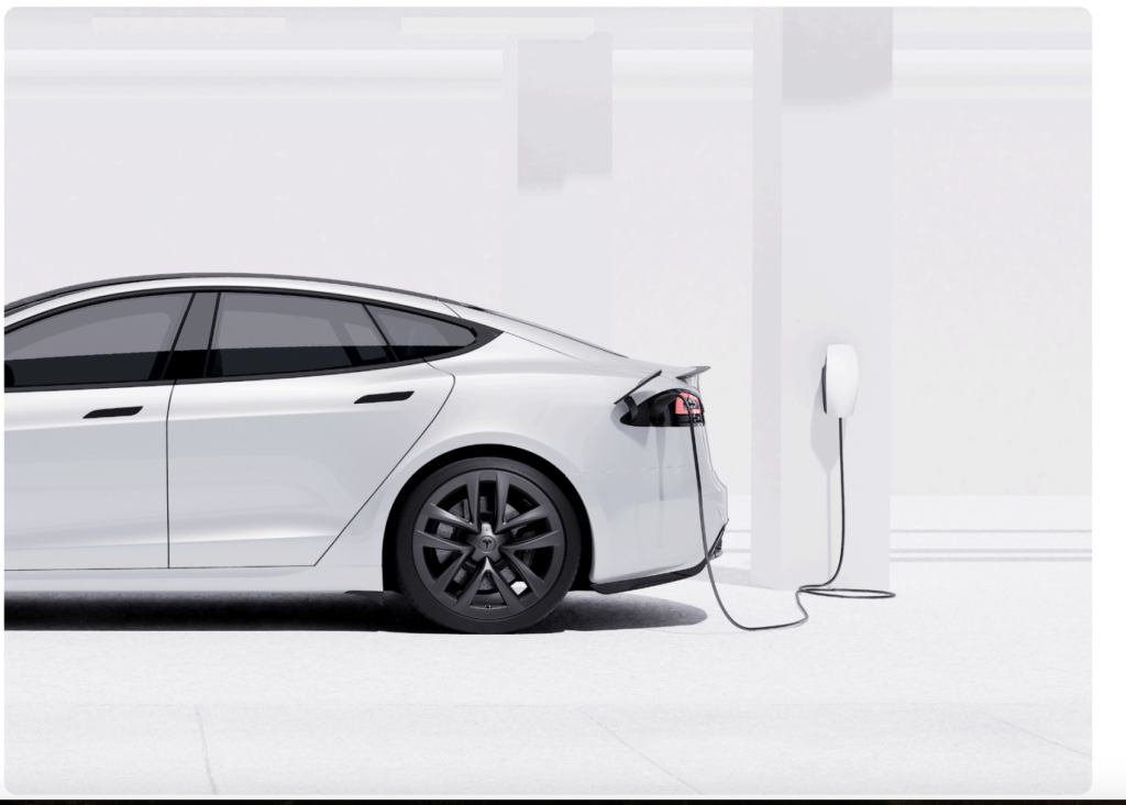 White electric car plugged into a wall charger in a bright minimalist garage setting seen from the rear side profile